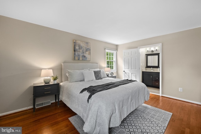 bedroom featuring baseboards, visible vents, wood finished floors, and a sink