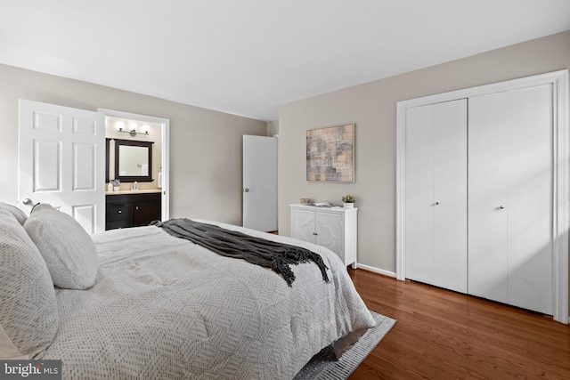 bedroom featuring ensuite bathroom, a closet, wood finished floors, and baseboards