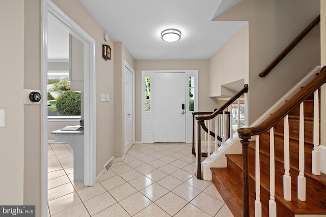 entrance foyer featuring light tile patterned floors, stairs, visible vents, and baseboards
