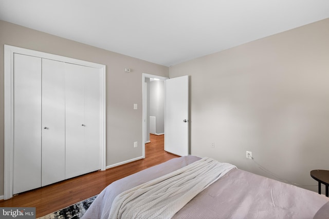 bedroom featuring wood finished floors, baseboards, and a closet