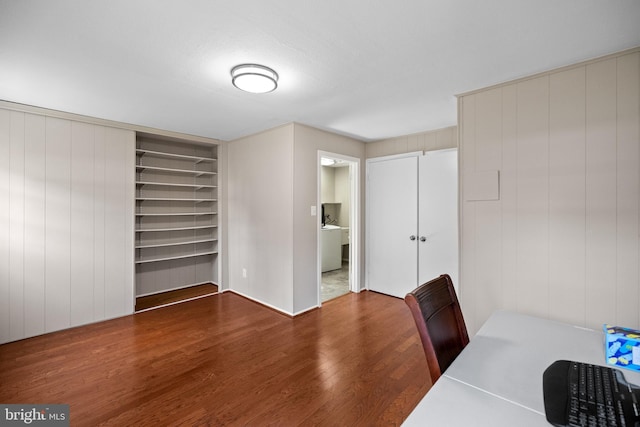 unfurnished office with built in shelves, washer / dryer, and wood finished floors
