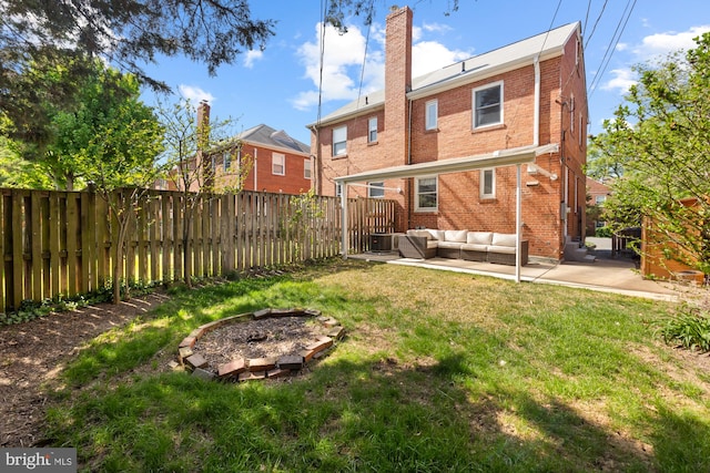 back of house featuring a fenced backyard, a chimney, brick siding, an outdoor living space, and a patio area