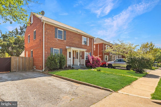 colonial house with brick siding, fence, and a front yard