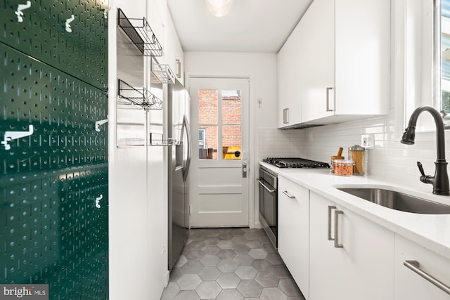 kitchen featuring decorative backsplash, stainless steel oven, light countertops, white cabinets, and a sink