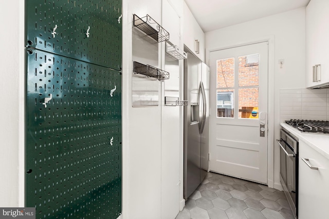 kitchen with light tile patterned flooring, light countertops, white cabinets, tasteful backsplash, and stainless steel appliances