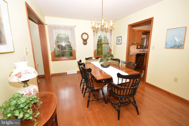 dining space featuring a chandelier, wood finished floors, and baseboards