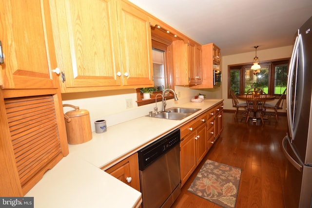 kitchen featuring stainless steel appliances, a sink, light countertops, and dark wood-style floors