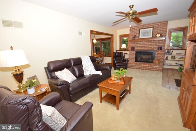living room featuring a brick fireplace, a ceiling fan, and light colored carpet