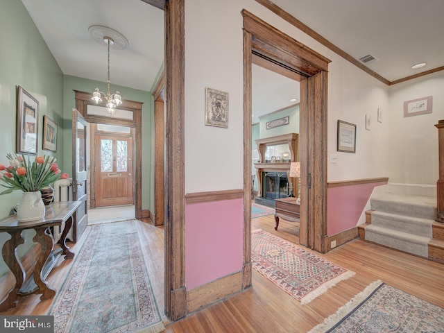 foyer with visible vents, stairs, wood finished floors, baseboards, and a chandelier
