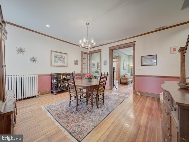 dining space featuring visible vents, crown molding, radiator heating unit, and a chandelier