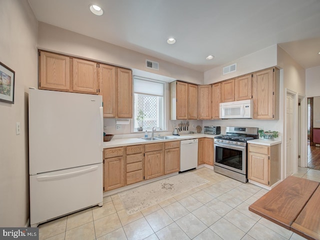 kitchen with visible vents, a sink, light tile patterned flooring, and white appliances