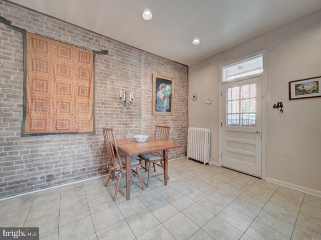 dining space featuring recessed lighting, radiator, light tile patterned flooring, and brick wall
