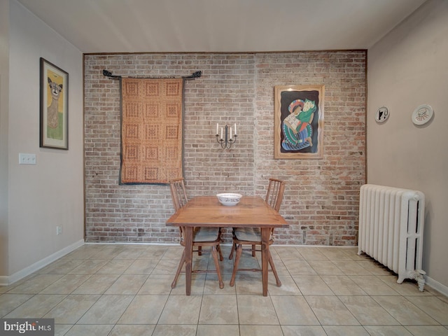 dining area featuring brick wall, light tile patterned floors, and radiator
