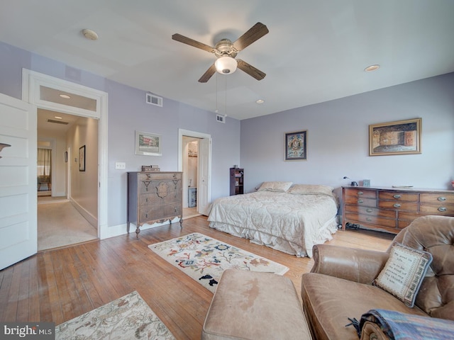 bedroom with baseboards, a ceiling fan, visible vents, and hardwood / wood-style floors