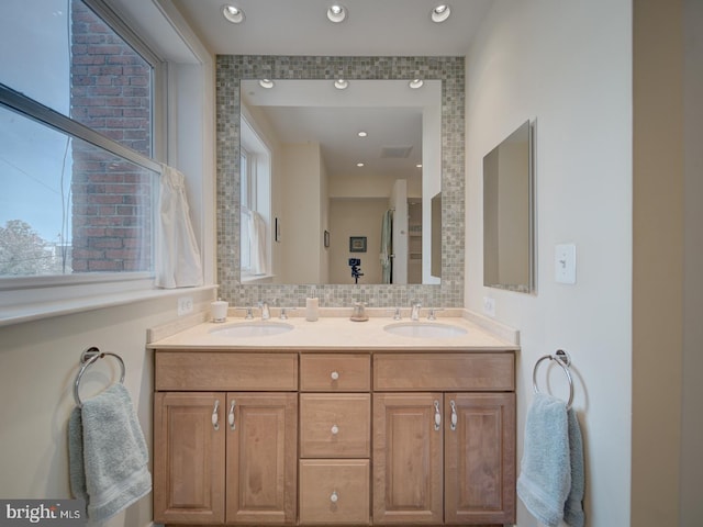 bathroom featuring a sink, decorative backsplash, recessed lighting, and double vanity