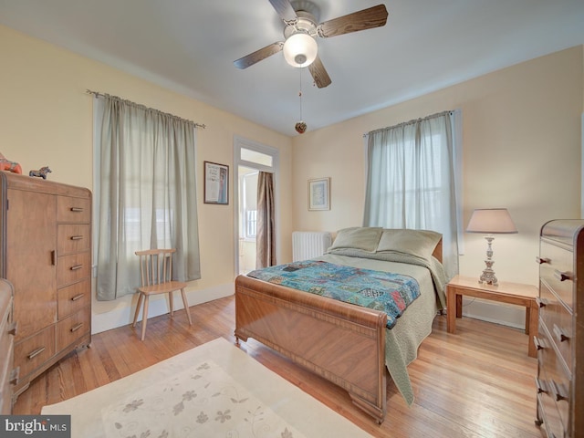 bedroom featuring ceiling fan, radiator heating unit, and light wood-type flooring