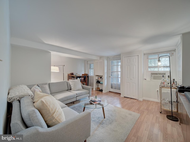 living room with baseboards, light wood finished floors, and cooling unit