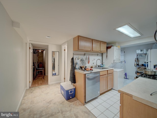 kitchen featuring stainless steel dishwasher, a sink, freestanding refrigerator, and light countertops