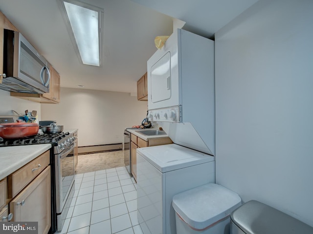 kitchen with light countertops, stainless steel appliances, baseboard heating, and stacked washer / dryer