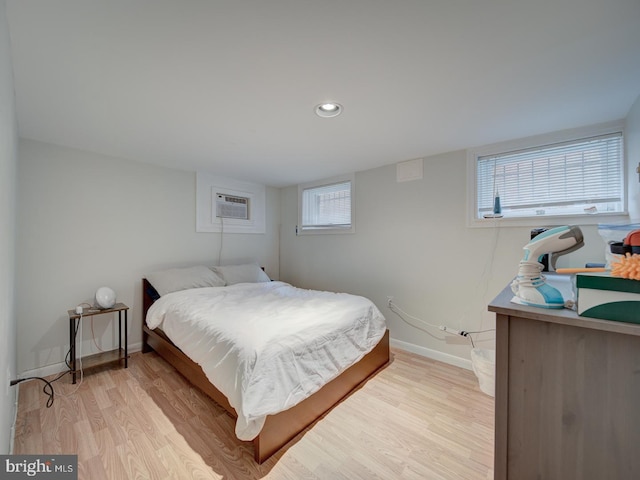 bedroom with recessed lighting, baseboards, an AC wall unit, and light wood-type flooring