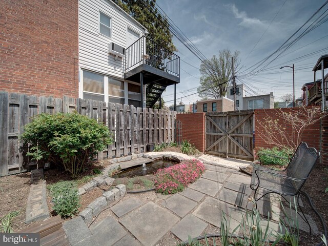 view of patio with a fenced backyard, a gate, and a wall mounted air conditioner