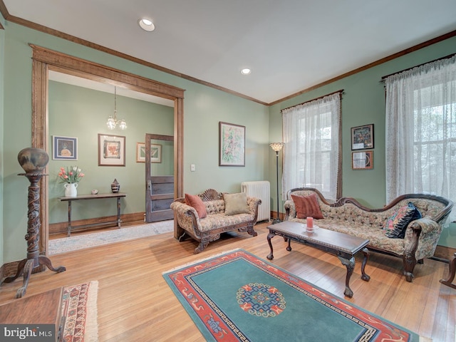 living area featuring radiator, ornamental molding, wood finished floors, and a notable chandelier