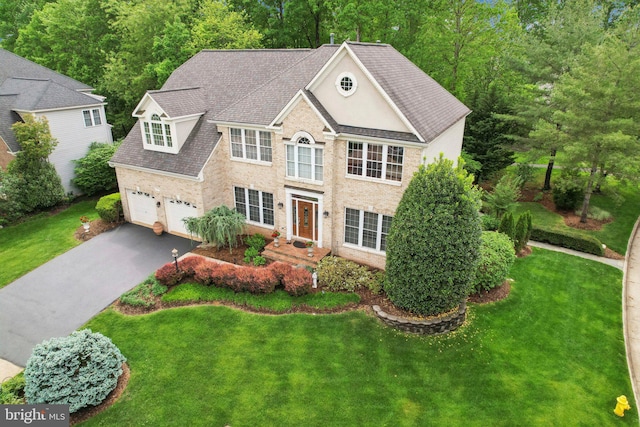 colonial home featuring a front yard, brick siding, and driveway