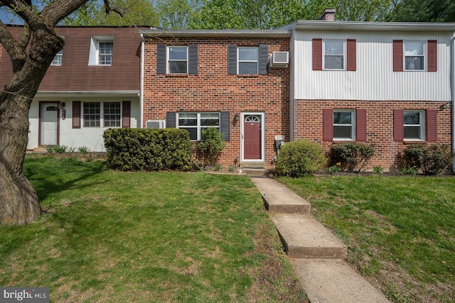 multi unit property featuring a wall mounted air conditioner, a chimney, a front lawn, and brick siding