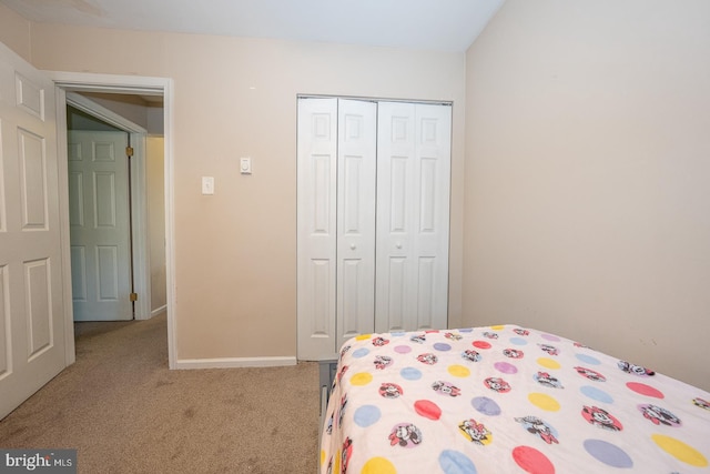 carpeted bedroom featuring a closet and baseboards