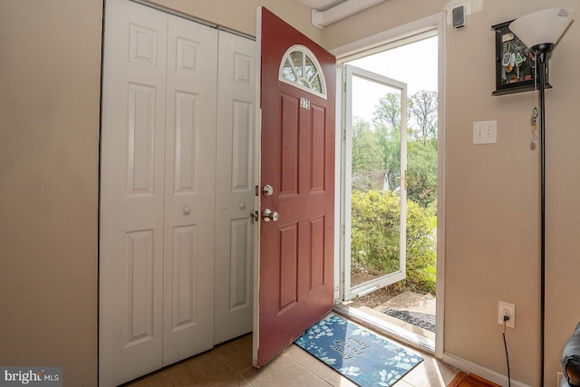 foyer entrance with light tile patterned floors and baseboards