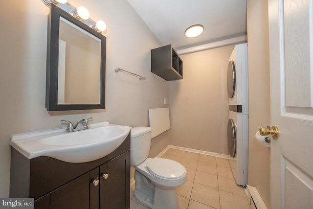 half bathroom with tile patterned flooring, vanity, toilet, stacked washing maching and dryer, and baseboards