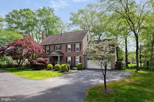 7228 Devereux Ct, Alexandria, VA 22315 - view of front facade with asphalt driveway, brick siding, a chimney, an attached garage, and a front lawn