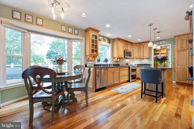 7228 Devereux Ct, Alexandria, VA 22315 - kitchen with stainless steel appliances, dark countertops, a sink, backsplash, and glass insert cabinets