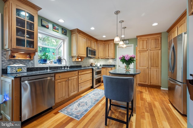 7228 Devereux Ct, Alexandria, VA 22315 - kitchen featuring appliances with stainless steel finishes, a sink, light wood finished floors, decorative backsplash, and a center island