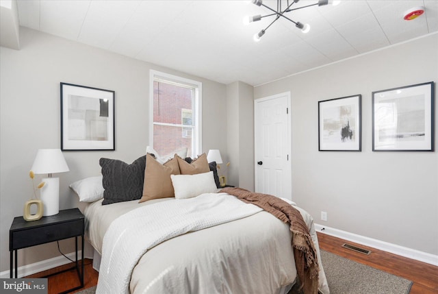 6217 Burgess Ave, Baltimore, MD 21214 - bedroom with wood finished floors, visible vents, baseboards, and a notable chandelier