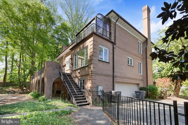 exterior space with stairway, brick siding, a chimney, and a garage