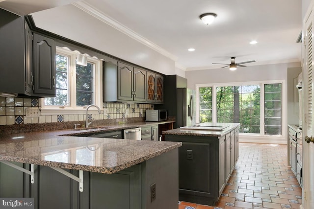 kitchen with a peninsula, a kitchen island, tasteful backsplash, a sink, and stainless steel appliances