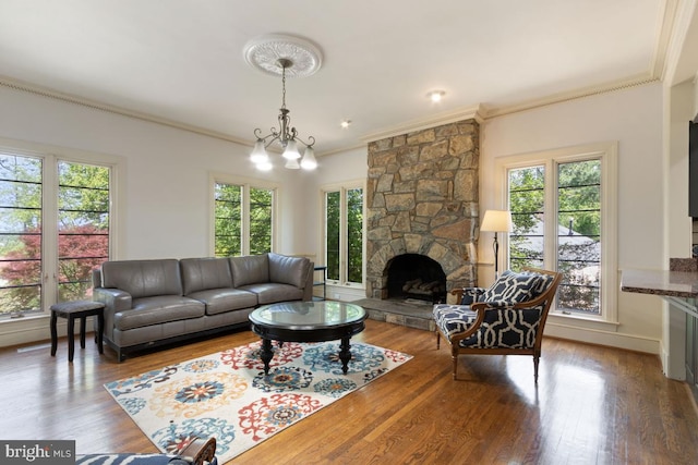 living area with crown molding, a wealth of natural light, and a stone fireplace