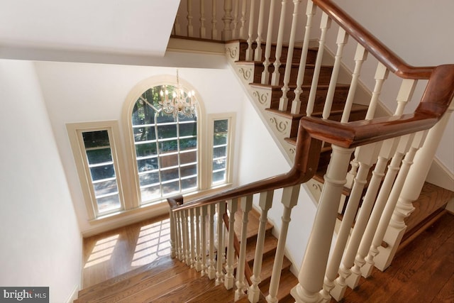 stairway with an inviting chandelier and hardwood / wood-style floors