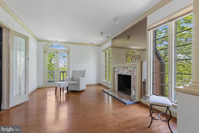 sitting room with crown molding, wood finished floors, baseboards, french doors, and a premium fireplace