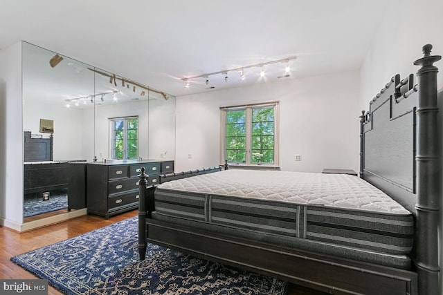 bedroom with track lighting and wood finished floors