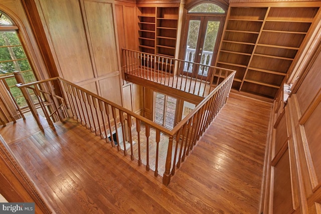 staircase with french doors, built in features, wood finished floors, and plenty of natural light