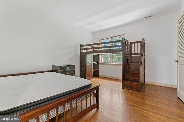 bedroom with visible vents, baseboards, and wood finished floors
