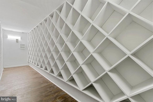 interior details with baseboards, a wall unit AC, and wood finished floors