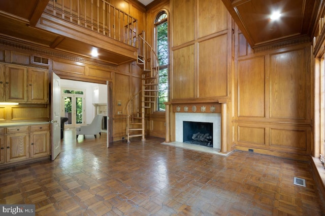 unfurnished living room with visible vents, wood walls, stairs, a decorative wall, and a premium fireplace