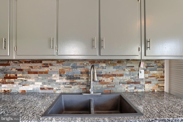 interior details with dark stone counters, decorative backsplash, and a sink