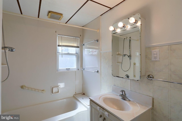 bathroom featuring tile walls, shower / bathing tub combination, and vanity