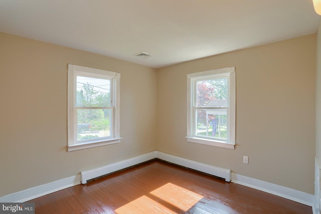 unfurnished room featuring wood-type flooring, visible vents, and baseboards