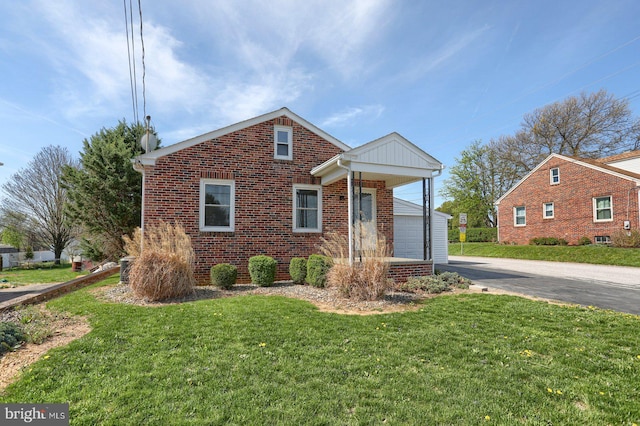view of front of house featuring a front lawn, brick siding, and driveway
