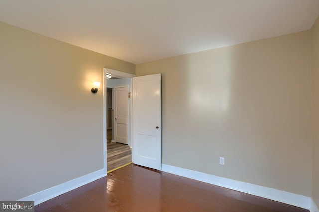 unfurnished room with baseboards and dark wood-style flooring